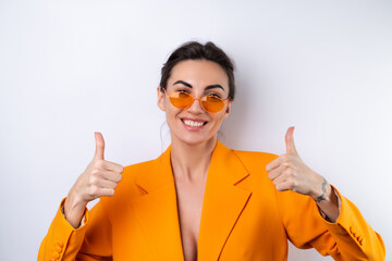 Wall Mural - Young woman in trendy stylish glasses and a bright orange oversized jacket on a white background