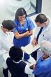 © Adene Sanchez/peopleimages.com - Together theyll find a cure. Shot of a group of doctors talking together over a medical chart while standing in a hospital.
