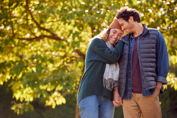 Wall Mural - Happy Loving Couple Holding Hands Walking In Autumn Park Together