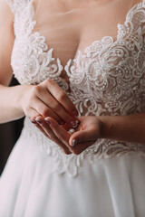 Wall Mural - The bride in an openwork dress holds a necklace in her hands 3794.