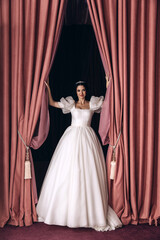 Wall Mural - Bride in a white wedding dress in the ceremonial hall. Significant day. Burgundy background.