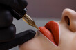 © руслан малыш - Cosmetologist makes permanent makeup on a woman's face. Specialist applies a tattoo on the patient's lips close-up