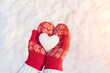 A snow heart in red mittens, a winter background on a background of light snow. Abstract postcard, conceptual love, romance, February 14, Valentine's Day.