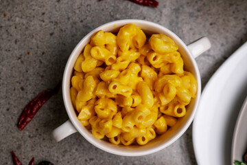 Poster - A top view of pasta in a white bowl with two handles, and dried chili peppers on the table