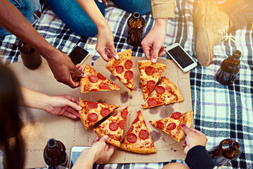 Pizza makes for the best picnics. Cropped shot of a group of friends eating pizza while having a picnic.