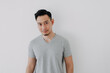 © Sevendeman - Portrait of Happy Asian man wear grey t-shirt stand isolated on white wall.