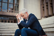 © Adene S/peopleimages.com - Trying to stay positive in the face of adversity. Shot of a dejected businessman sitting on the stairs outside his office with his head in his hands.