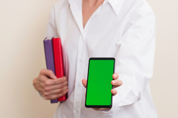 Wall Mural - Woman hands holding books and smartphone with blank green screen background