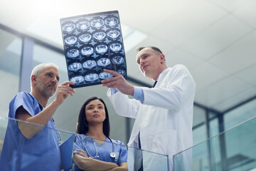 Canvas Print - Examining the patients latest scans. Shot of a group of doctors looking at a medical scan while standing in a hospital.