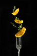 A slice of fried potatoes on a fork and flying potatoes and arugula on a black background.