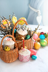 Canvas Print - Easter cakes (kulich), candle, colorful eggs and willow branches in basket on table. Festive composition. Easter holiday background