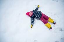 Cute Girl Making Snow Angel During Winter.