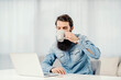 © Dusan Petkovic - A bearded entrepreneur drinking his coffee and looking at laptop at home.