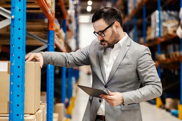 Wall Mural - A warehouse inspector looking at box with tablet in hands and checking on order.