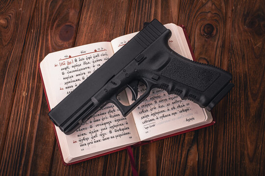 The gun lies on an open bible on a wooden table, soft focus
