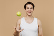 © ViDi Studio - Attractive excited happy young man 20s perfect skin in undershirt toss up green apple fruit isolated on pastel pastel beige background studio portrait Skin care healthcare cosmetic procedures concept