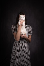 Studio Portrait Of Woman In Polkadot Dress Holding White Cat