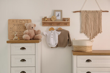 Wall Mural - Wooden shelf with baby clothes, toys and furniture in room. Interior design