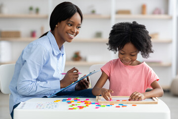 Wall Mural - Female psychologist working with little girl at office