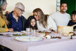 © DisobeyArt - Latin grandmother kissing her grand-daughter during home family dinner - Focus on girl face