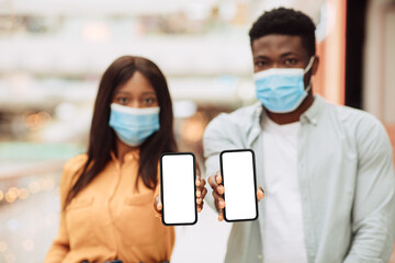 Black couple in masks showing blank empty smartphone screen