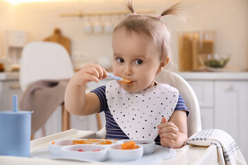 Canvas Print - Cute little baby eating food in high chair at kitchen