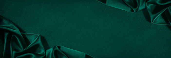 Wall Mural - Dark green silk satin background. Beautiful soft folds on the smooth surface of the fabric. Luxury background with copy space for design. Wide banner. Top view. Flat lay.