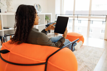 Wall Mural - Smiling black woman using tablet at home, mockup