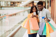 © Prostock-studio - Portrait of happy black couple using smartphone holding credit card