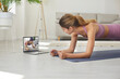 © Studio Romantic - Strong, active woman doing sports workout on floor mat at home, having online class with sportswoman, following professional instructions, practicing calorie burning forearm elbow plank pose exercise