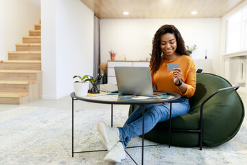 Canvas Print - Happy woman holding debit credit card, using pc