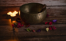 Handmade Tibetan Bowl With Flower Petals And Candles In Dim Light