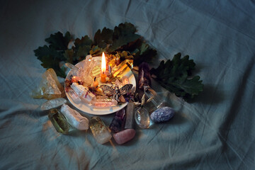 gemstones, candle, amulet, leaves on fabric abstract dark background. witch Esoteric spiritual Ritual. aura cleansing. modern wicca and paganism concept