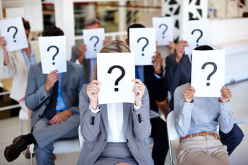 Sticker - Shed a little light on this. Shot of a group of businesspeople holding up signs with question marks on them during a work presentation.