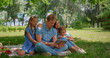 © stockbusters - Young family sitting with tablet on sunny park. Happy people use laptop outdoors