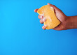 A studio shot of a soapy sponge being squeezed on a blue background