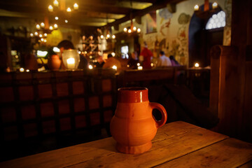 Clay jug with beer on a wooden table in a medieval tavern.