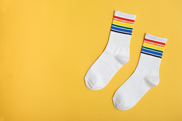 Wall Mural - white cotton socks with rainbow colors on yellow background, LGBTQ symbol, gift idea