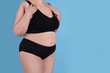 © New Africa - Overweight woman in underwear on light blue background, closeup. Space for text