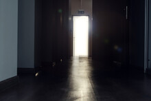 Bright Light Coming Out Of The Door In The End Of A Dark Hallway