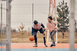 © Drazen - Happy athletic man with leg prosthesis and his girlfriend play basketball on an outdoor court.