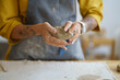 © DimaBerlin - Female potter artist molding raw clay. Closeup of woman ceramist in dirty apron prepare for shaping pottery. Craftswoman hands work with earthenware. Art studio production and craftsmanship therapy