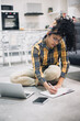 © Cavan Images - young Afro woman working from home sitting on floor with her laptop