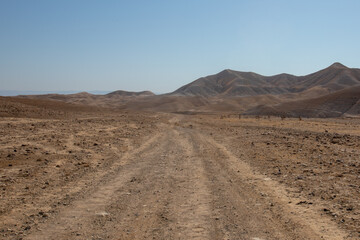 Beautiful landscape of Israeli Judean Desert mountains, with sunrise over the dry riverbed of Nahal Dragot Wadi, popular hiking trail winding between rugged rocky cliffs towards the Dead Sea. High