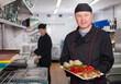 © JackF - Smiling chef presenting delicious cooked dish in restaurant kitchen, ready to serve it to guests