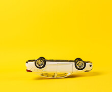 Upside Down Model Of A Toy Car On A Yellow Background. Car Accident
