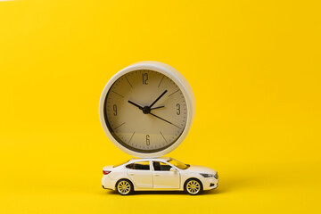 Toy car model with clock on yellow background