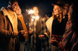 © StratfordProductions - Group of young adult Multi-cultural friends laughing at a rooftop party with sparklers