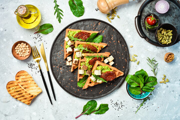 Wall Mural - Belgian waffles with avocado pate, sun-dried tomatoes and tofu cheese. The concept of healthy eating. On a stone background. Top view.