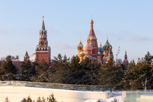 A Winter Shot Of The Moscow Kremlin And St. Basil's Cathedral In The Background And The Coniferous Trees Of Zaryadye Park In The Foreground. Snow On The Ground. Famous Tourist Places